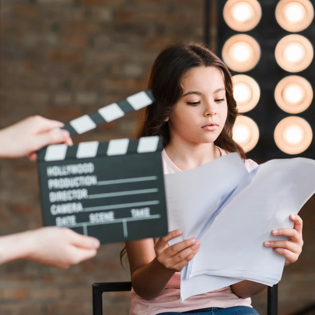 [fpdl.in]_hand-holding-clapper-board-front-girl-reading-scripts-studio_23-2147882960_full